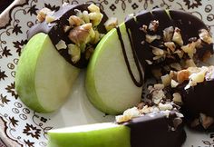 two pieces of chocolate covered apples on a plate with nuts and walnuts in the center