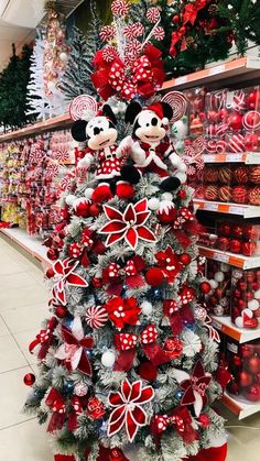 a christmas tree with mickey and minnie mouse decorations on it in a grocery store aisle