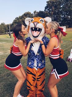 three cheerleaders pose with a tiger mascot