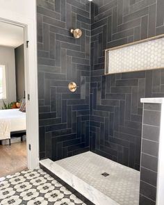 a walk in shower sitting next to a white door and black tiled floored wall