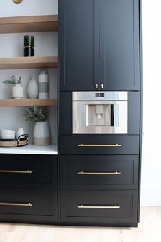 an oven built into the side of a black cabinet with gold handles and brass pulls