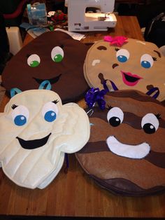 four oven mitts with faces on them sitting on a table