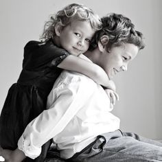 two young children hugging each other while sitting on top of a bed in black and white