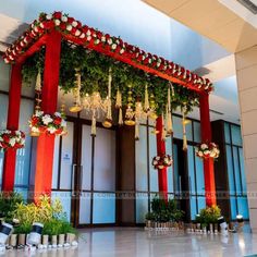 the entrance to an office building decorated with red and white flowers, bells and greenery