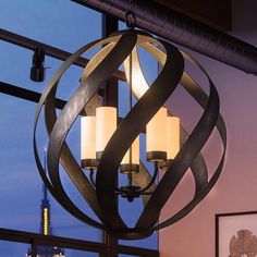 a chandelier hanging from the ceiling in front of a window with city lights