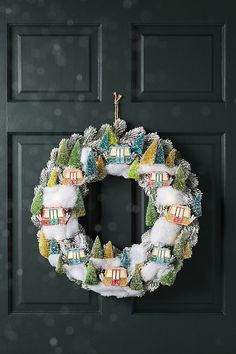 a wreath hanging on the front door of a house decorated with snow and christmas decorations