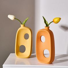 two vases with flowers in them sitting on a table next to each other,