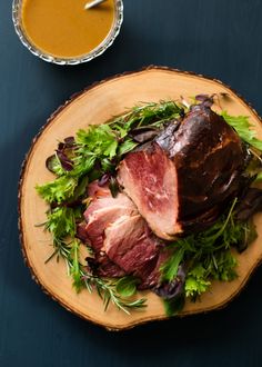 a wooden plate topped with meat and veggies next to a cup of soup