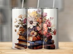 three books with flowers on them are sitting next to each other in front of a wooden table