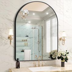 a bathroom with marble counter tops and a large oval mirror over the sink that has flowers in front of it