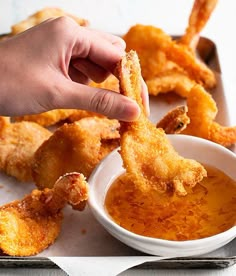 a person dipping some food into a bowl