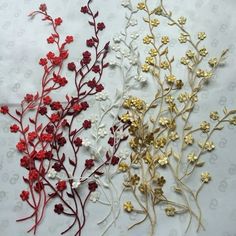 three different types of flowers on a white tablecloth with gold and red stems in the center