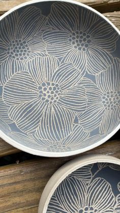 two bowls sitting next to each other on top of a wooden table with flowers painted on them