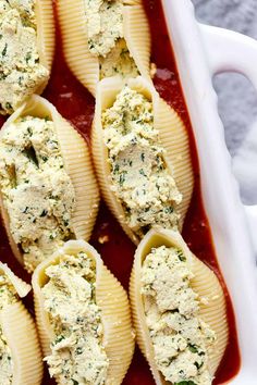 pasta shells stuffed with cheese and sauce in a white casserole dish