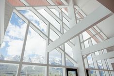 the inside of a building with large windows and mountains in the background on a sunny day