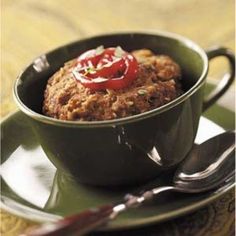 a bowl filled with food sitting on top of a green plate next to a fork