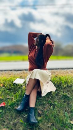 a woman sitting in the grass with her hands behind her head