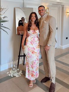 a man and woman standing next to each other in front of a mirror with flowers on it