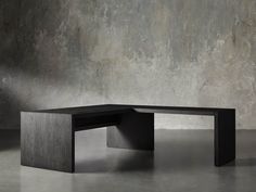 a black table sitting on top of a cement floor next to a gray concrete wall