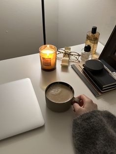 a person sitting at a desk with a cup of coffee in front of a laptop