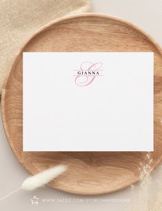 a place card on a wooden plate next to a feather