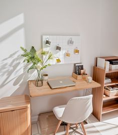 a laptop computer sitting on top of a wooden desk next to a white chair and book shelf