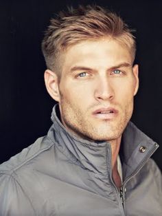 a man with blonde hair wearing a gray jacket