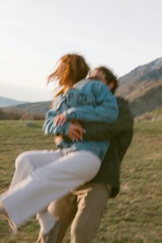 two people are playing with each other in the grass and one person is holding on to his back