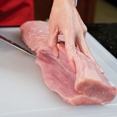 a person cutting up meat on top of a white counter next to a pair of scissors