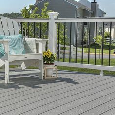 a white chair sitting on top of a wooden deck next to a fence and flowers