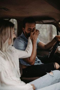 a man and woman sitting in the back seat of a car