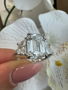 This 14K White Gold Engagement Ring features a stunning 4CT Emerald Cut Lab Grown Diamond Center Stone with Trapezoid Cut side stones of 0.75CT each. This engagement ring style is a true eye catcher. Metal Material: 14K White Gold Lab Grown Diamond: 4CT Emerald Shape Center and 0.75CT Each Trapezoid Cut Sidestones Shape: Emerald Cut & Trapezoid Cut Color: E Clarity: VS1 Cut: Excellent 3 Stone Emerald Engagement Rings, Dream Wedding Ring, Wedding Rings Princess Cut, Lab Grown Diamond Engagement Ring, Chic Rings, Future Engagement Rings, Lab Grown Diamonds Engagement, Dream Engagement Rings, Emerald Engagement Ring