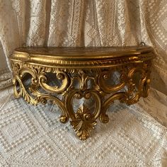 an ornate gold metal shelf on a white fabric