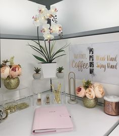 there is a desk with flowers and office supplies on it