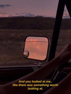 a woman driving in the back seat of a car at sunset with her hand on the steering wheel