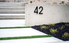 the number 42 is displayed in front of a concrete planter with grass and flowers