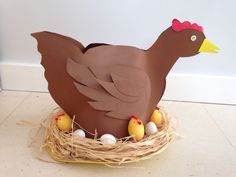 a paper mache chicken sitting in a nest with eggs