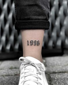 a person with a small tattoo on their ankle that reads,'1909'in black ink