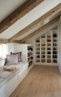 an attic bedroom with white walls and wooden flooring, built in shelving units