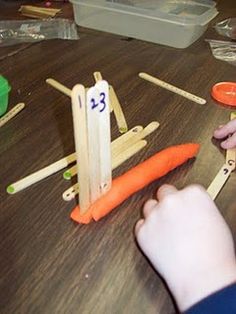 a child is playing with wooden sticks and carrots that are numbered 3 - 5