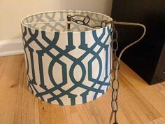 a white and blue lamp shade sitting on top of a wooden floor next to a black box