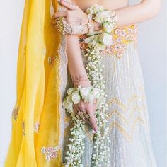 a woman in a white and yellow dress with flowers on her arm