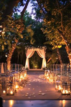 an outdoor wedding venue with candles lit up in the trees and flowers on the ground