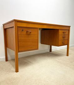 a wooden desk with two drawers on it's sides and a white wall in the background