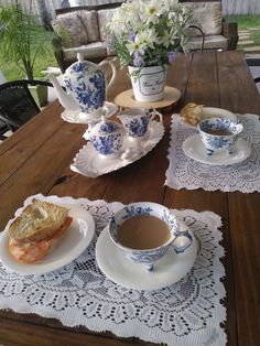 a table topped with plates and cups filled with tea on top of a wooden table