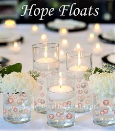 there are candles that are on the table with flowers in vases and pearls around them