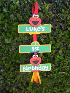 a street sign that says luke's 1st birthday and elm street with two sesame street signs hanging from it