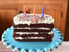 a piece of chocolate cake with white frosting and sprinkles on a blue plate