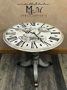 an old clock sits on top of a wooden table in front of a sign with the words m & s embellishments