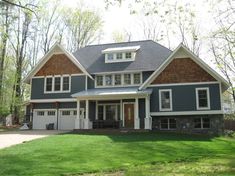 a large gray and white house in the middle of a green yard with lots of trees